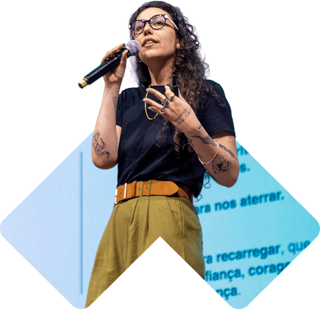 Mulher apresentando em um palco, com um telão ao fundo mostrando gráficos e números relacionados ao mercado do morar